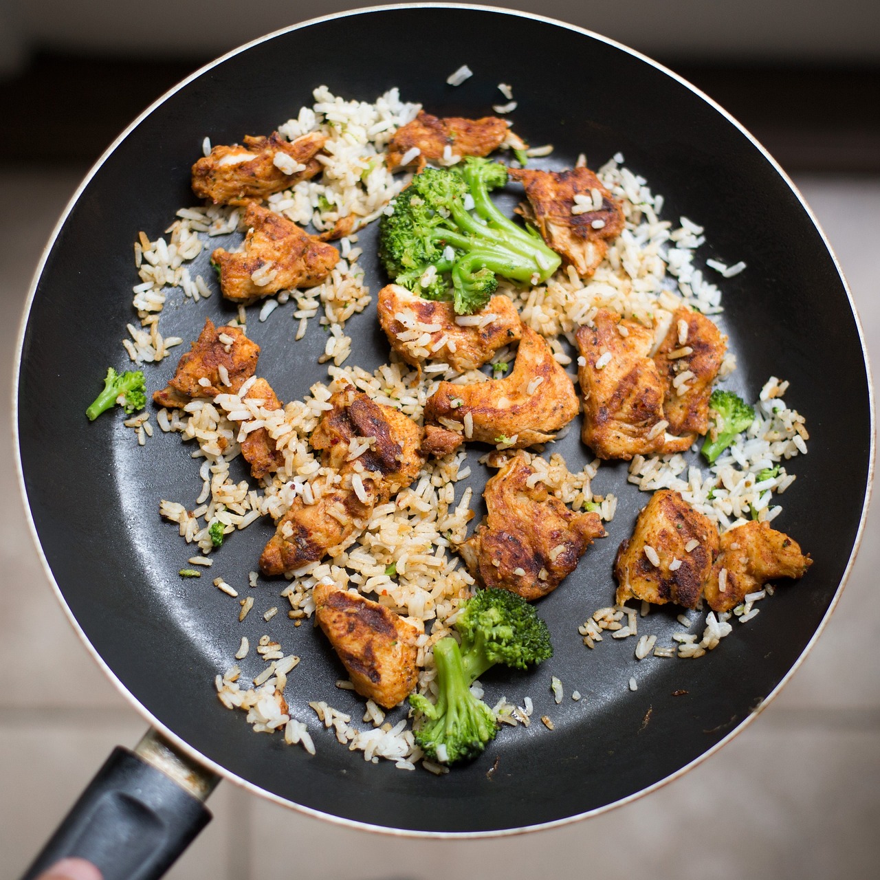 Golden cast-iron skillet of smothered chicken and rice on a linen-dressed table.